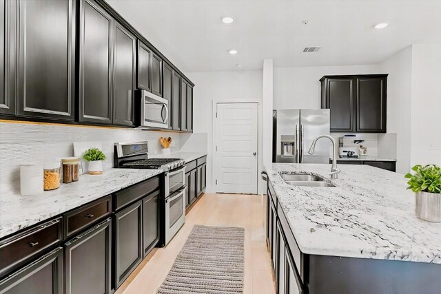 7411 Merrick Ln Unit 39, Austin, TX 78745 - kitchen with stainless steel appliances, a sink, light stone countertops, recessed lighting, and dark cabinetry