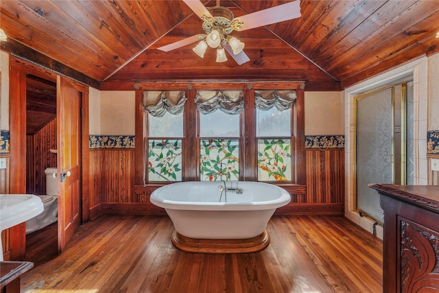 bathroom featuring hardwood / wood-style flooring, wooden walls, wood ceiling, and a tub to relax in