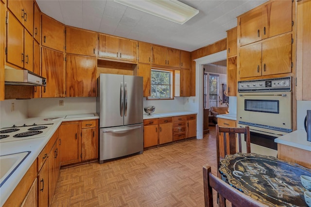 kitchen with stainless steel refrigerator, white electric cooktop, and light parquet floors