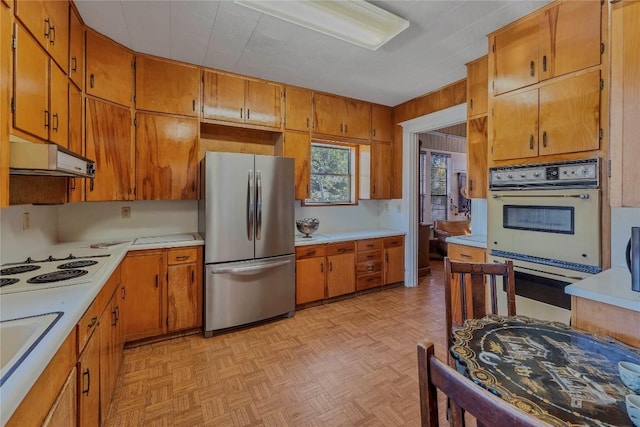 524 Saint Peter St, Gonzales, TX 78629 - kitchen featuring white appliances, light countertops, brown cabinetry, and extractor fan