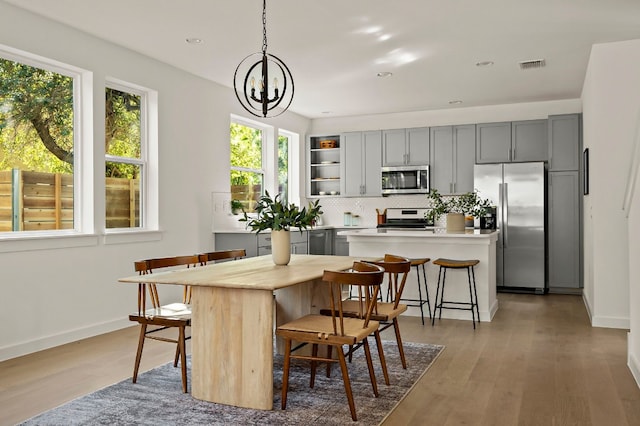 kitchen featuring gray cabinetry, a center island, a chandelier, pendant lighting, and appliances with stainless steel finishes