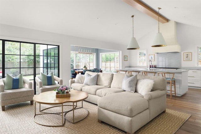 living room with light wood-type flooring, lofted ceiling with beams, and sink