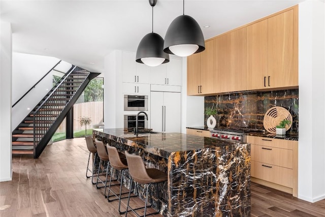 kitchen featuring a sink, tasteful backsplash, paneled refrigerator, and light brown cabinets