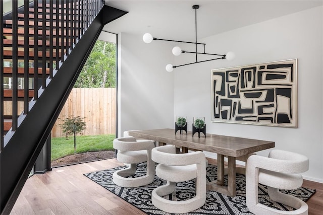 dining area with a notable chandelier, floor to ceiling windows, and wood finished floors