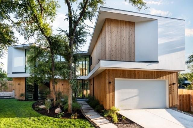 contemporary house featuring driveway, a garage, fence, and a front lawn