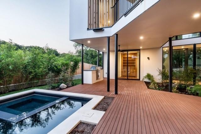 exterior space featuring a deck, area for grilling, fence, and a fenced in pool