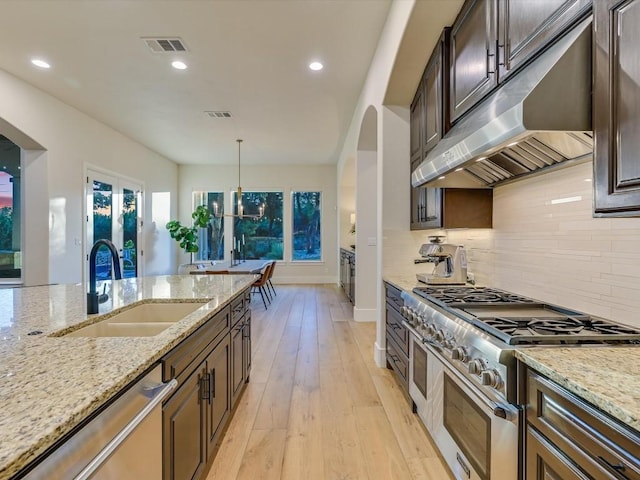 kitchen featuring light stone countertops, appliances with stainless steel finishes, decorative light fixtures, and sink