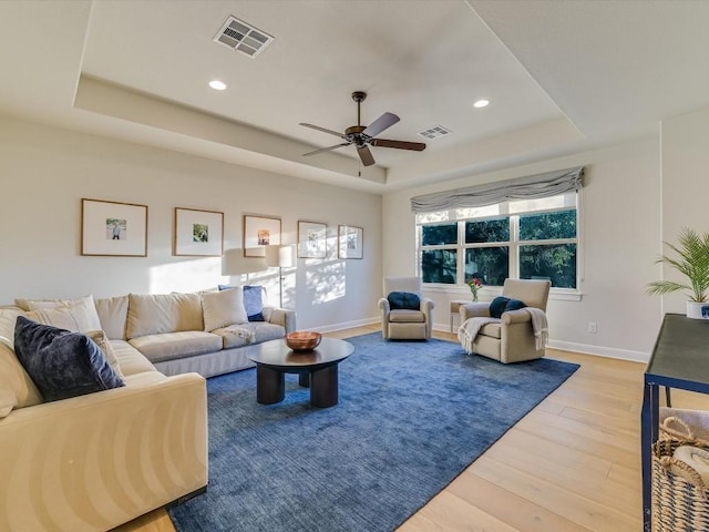 living room featuring a tray ceiling, hardwood / wood-style flooring, and ceiling fan