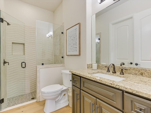 bathroom with hardwood / wood-style floors, vanity, toilet, and a shower with door