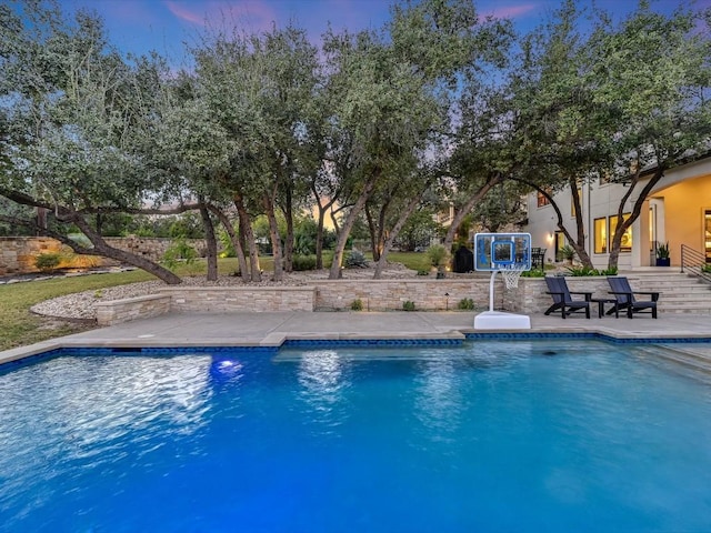 pool at dusk featuring a patio area