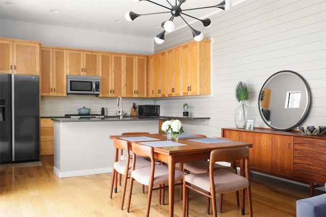 kitchen with tasteful backsplash, black fridge with ice dispenser, light hardwood / wood-style floors, and an inviting chandelier