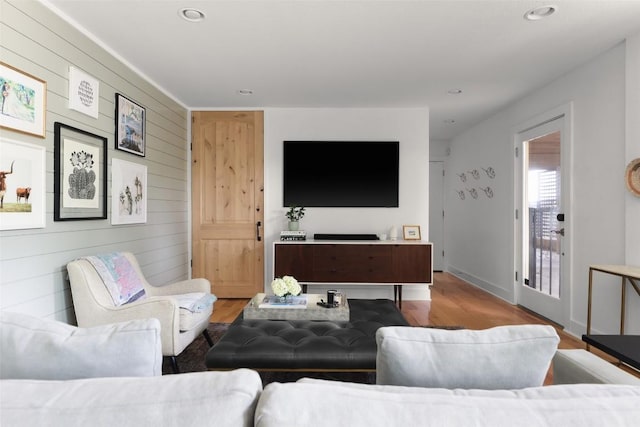 living area featuring recessed lighting, wood finished floors, baseboards, and wood walls