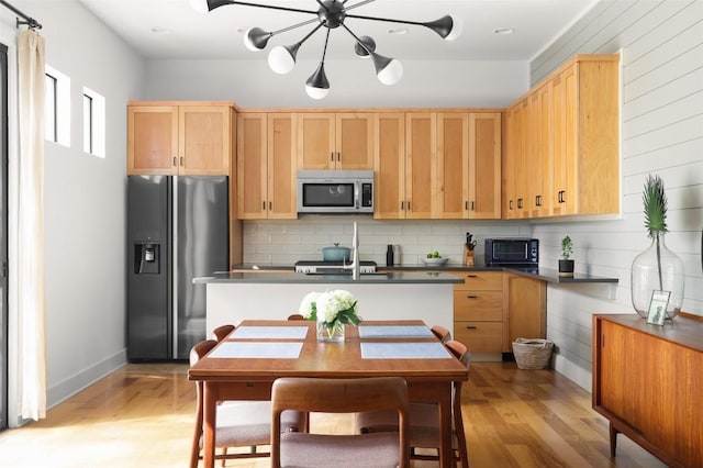 kitchen featuring stainless steel appliances, backsplash, light brown cabinets, and light wood finished floors