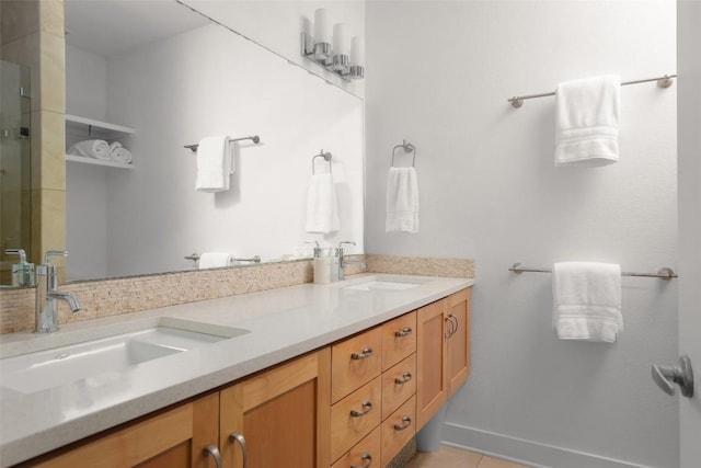 full bathroom with a sink, a shower with door, double vanity, and tile patterned flooring