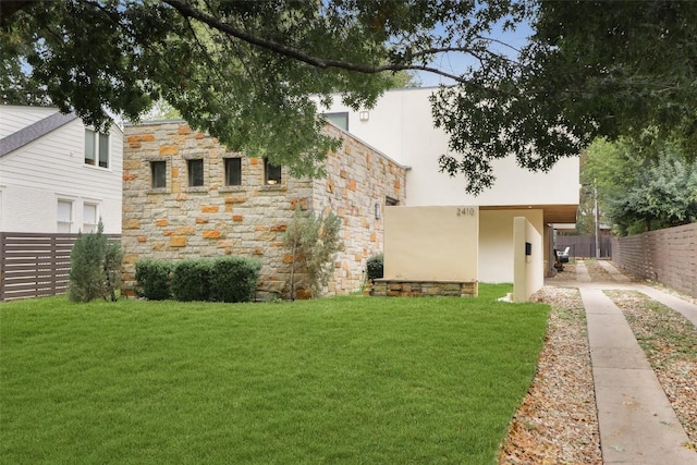 exterior space with stone siding, stucco siding, a yard, and fence