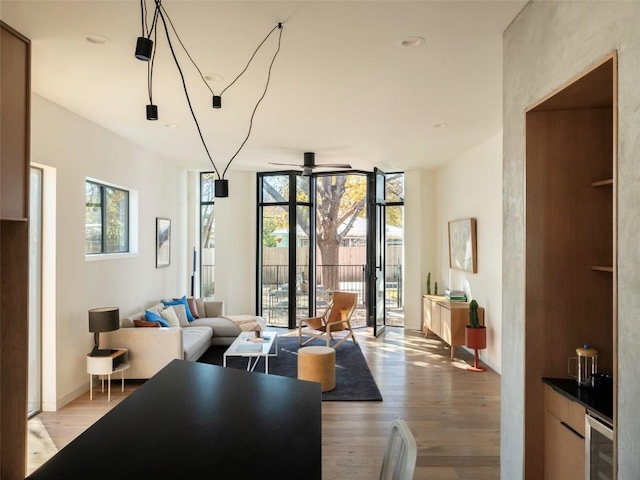 living room with ceiling fan, plenty of natural light, light hardwood / wood-style floors, and a wall of windows