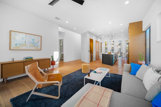 living room featuring light hardwood / wood-style flooring, ceiling fan, and sink