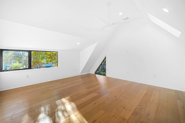 bonus room with ceiling fan, vaulted ceiling with skylight, and light hardwood / wood-style floors