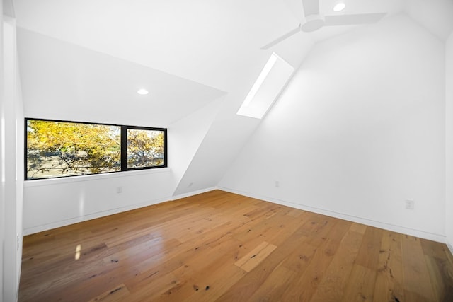 additional living space featuring lofted ceiling with skylight, hardwood / wood-style floors, and ceiling fan