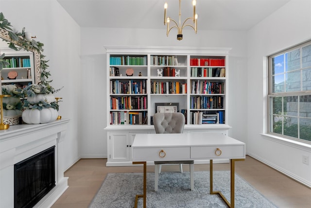 office with an inviting chandelier, light hardwood / wood-style floors, and a healthy amount of sunlight