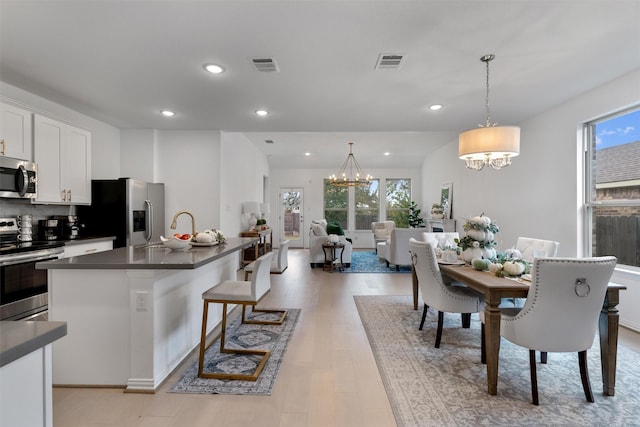 kitchen with an inviting chandelier, white cabinetry, light hardwood / wood-style floors, pendant lighting, and appliances with stainless steel finishes