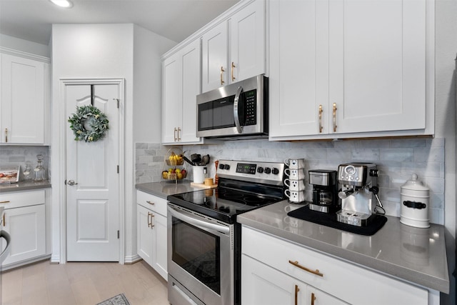 kitchen with stainless steel appliances, white cabinetry, light wood-type flooring, and backsplash