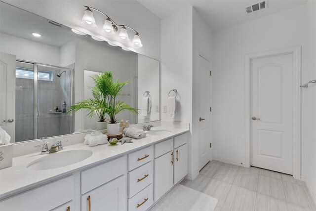 bathroom featuring a shower with door and vanity