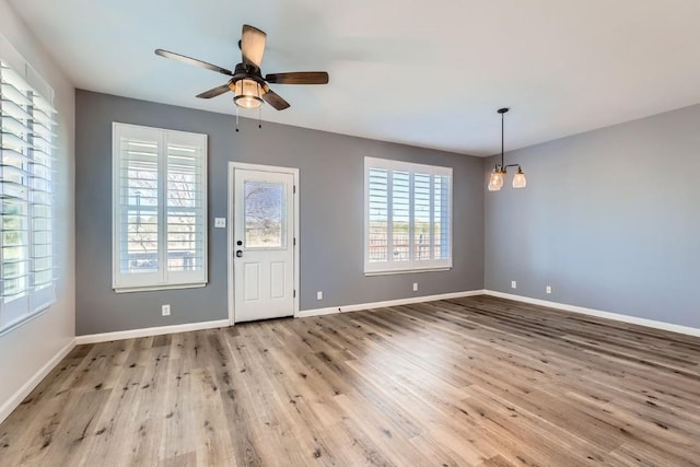 foyer with ceiling fan with notable chandelier and light wood-type flooring