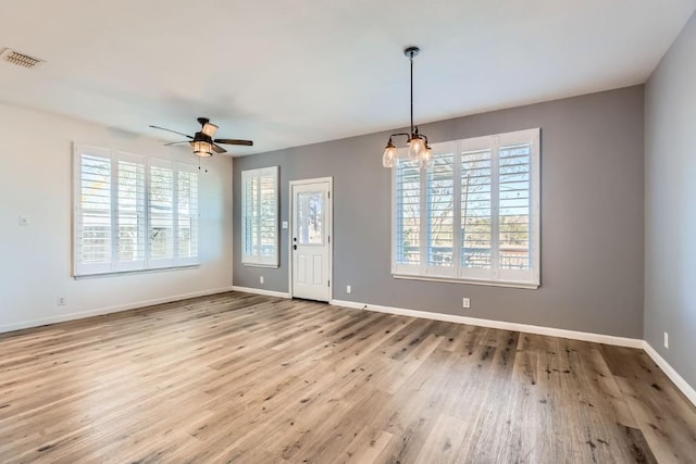 interior space with ceiling fan with notable chandelier and light wood-type flooring