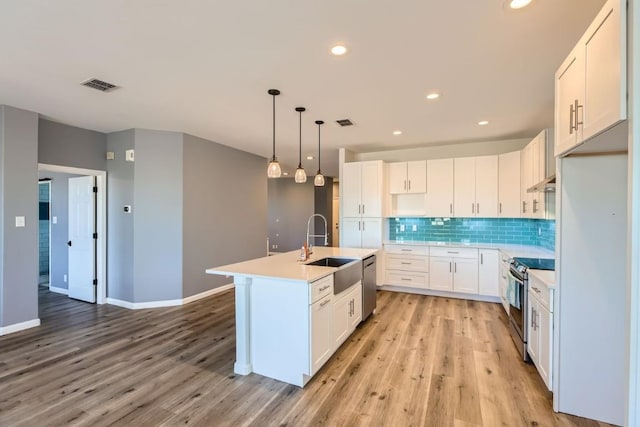 kitchen featuring pendant lighting, white cabinets, sink, an island with sink, and stainless steel appliances