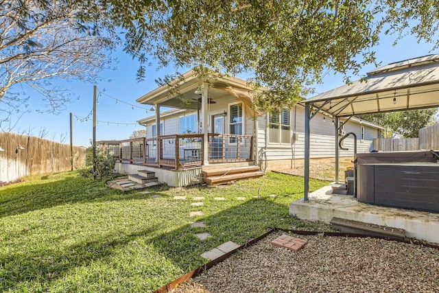 rear view of house featuring a gazebo, a yard, a hot tub, and a deck