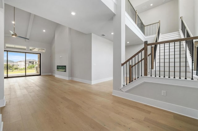 917 Bristol Creek Bnd, Lakeway, TX 78738 - unfurnished living room with high vaulted ceiling, ceiling fan, stairway, wood finished floors, and a large fireplace