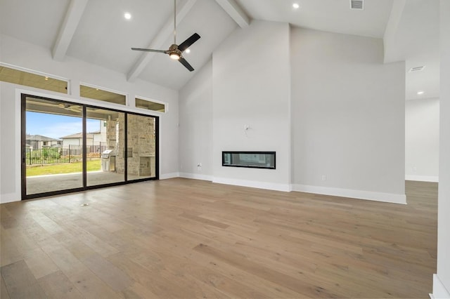 917 Bristol Creek Bnd, Lakeway, TX 78738 - unfurnished living room featuring high vaulted ceiling, beamed ceiling, ceiling fan, wood finished floors, and a glass covered fireplace