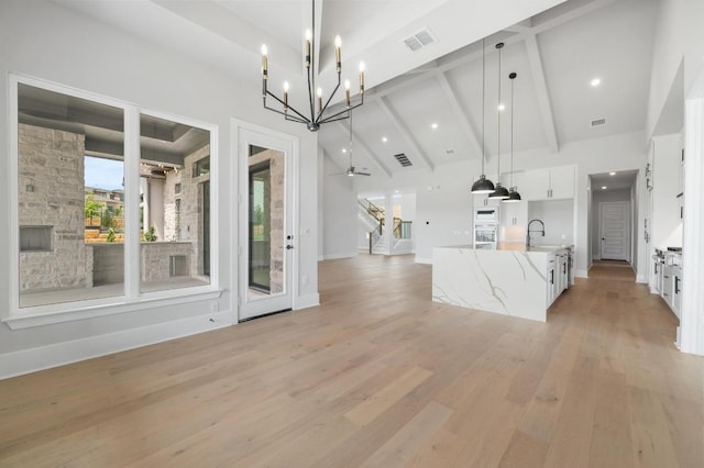 917 Bristol Creek Bnd, Lakeway, TX 78738 - unfurnished living room with high vaulted ceiling, light wood-style floors, stairs, a chandelier, and beamed ceiling
