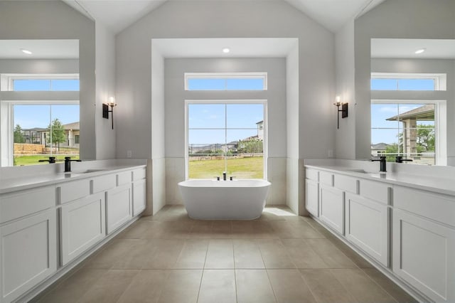 917 Bristol Creek Bnd, Lakeway, TX 78738 - bathroom with lofted ceiling, two vanities, a soaking tub, tile patterned flooring, and a wainscoted wall