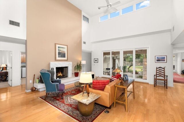 living room featuring hardwood / wood-style floors, a towering ceiling, ceiling fan, and a premium fireplace