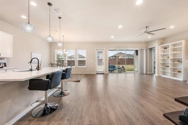 kitchen with hardwood / wood-style floors, a breakfast bar, white cabinets, sink, and hanging light fixtures