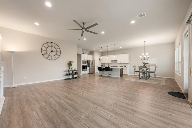 unfurnished living room featuring ceiling fan with notable chandelier, light hardwood / wood-style flooring, and sink