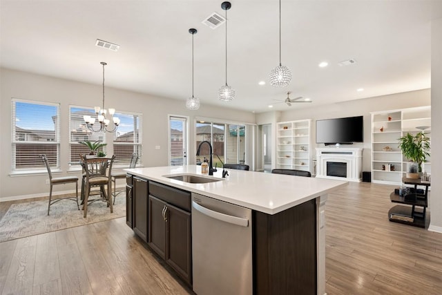 kitchen featuring sink, hanging light fixtures, stainless steel dishwasher, an island with sink, and ceiling fan with notable chandelier