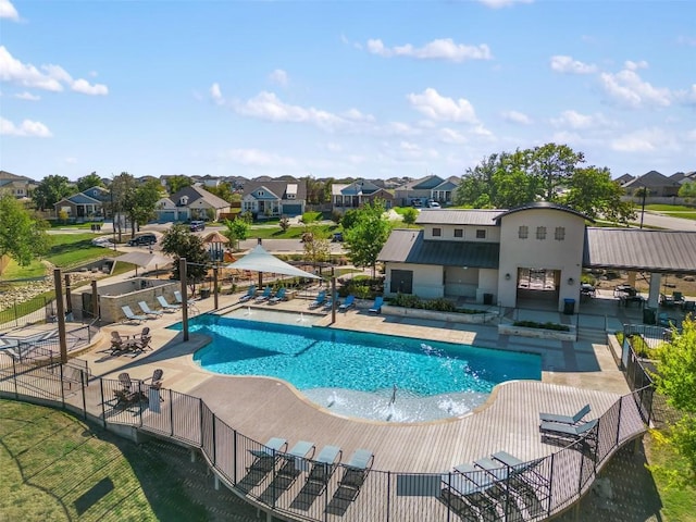 community pool with a patio, a residential view, and fence