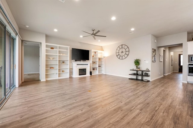 132 Ridgeview Ct, Georgetown, TX 78628 - living room featuring a glass covered fireplace, ceiling fan, light wood-style flooring, recessed lighting, and built in shelves