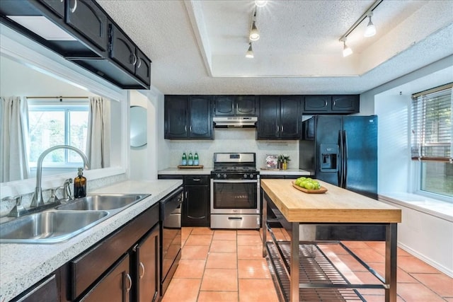 kitchen with a textured ceiling, a tray ceiling, sink, black appliances, and light tile patterned floors