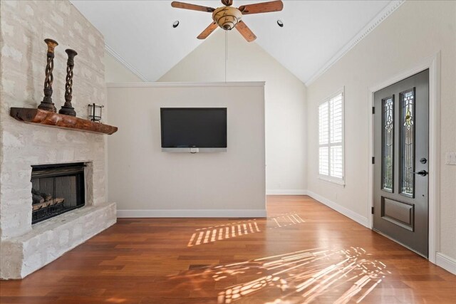 unfurnished living room with lofted ceiling, wood-type flooring, a large fireplace, ornamental molding, and ceiling fan