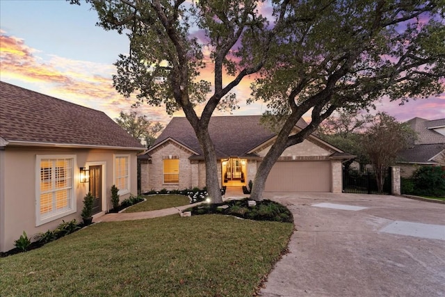 view of front facade featuring stucco siding, a shingled roof, a front yard, a garage, and driveway