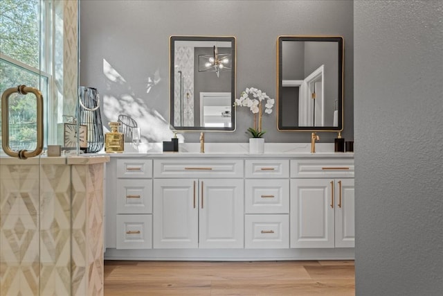 full bathroom featuring double vanity, wood finished floors, and a textured wall