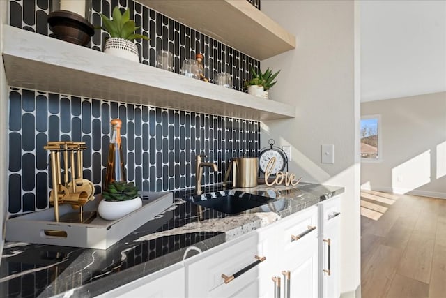 bar featuring a sink, decorative backsplash, and wood finished floors