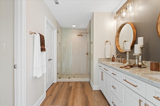 bathroom with a shower with shower door, hardwood / wood-style flooring, and vanity