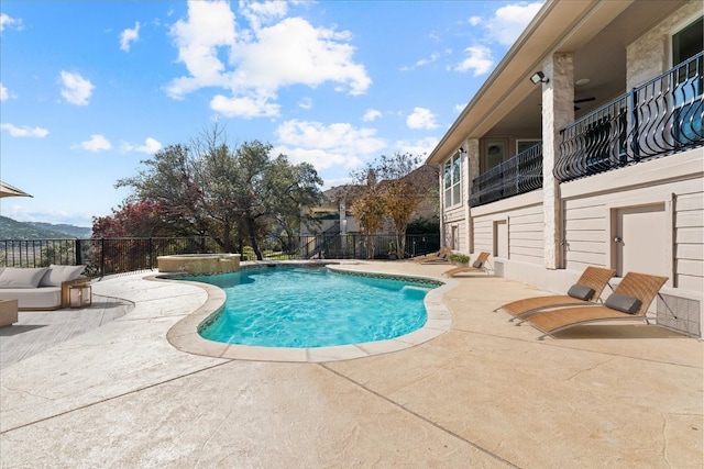 view of swimming pool featuring a pool with connected hot tub, a patio area, fence, and a mountain view