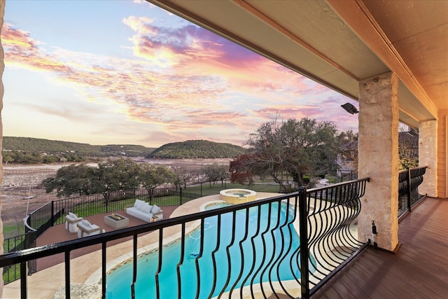 balcony at dusk featuring a mountain view, an in ground hot tub, and an outdoor living space