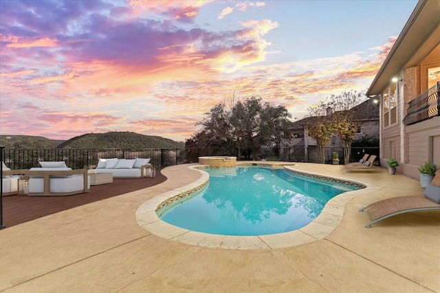 pool at dusk with a fenced in pool, a patio area, a fenced backyard, and an outdoor living space